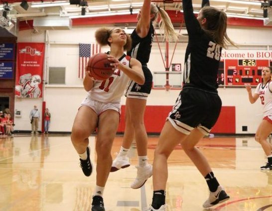 a player jumps to make a shot against two others