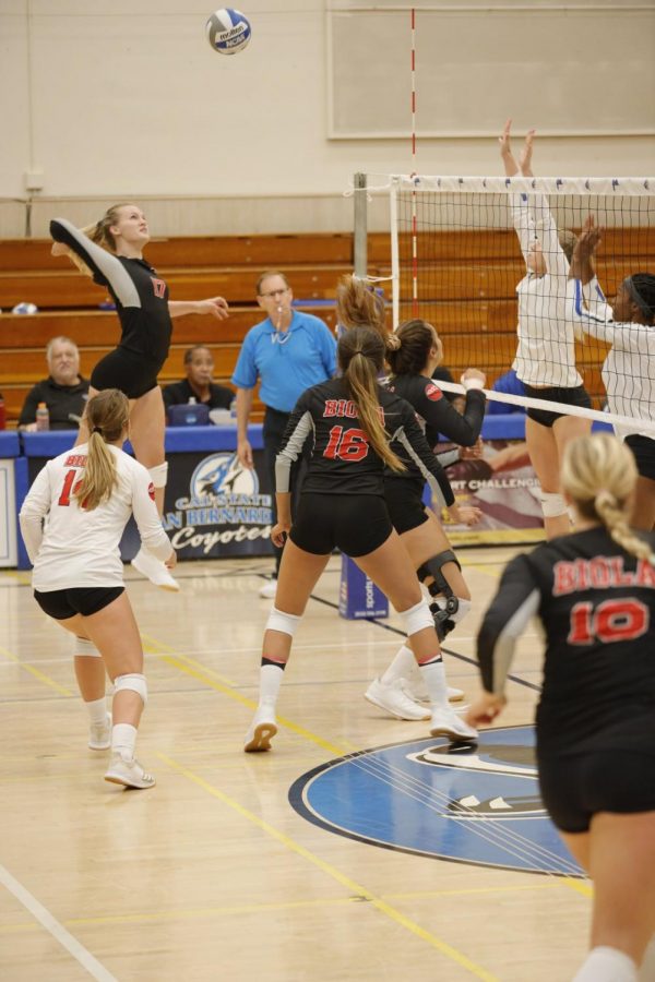 Biola volleyball athlete jumps to spike the ball. 