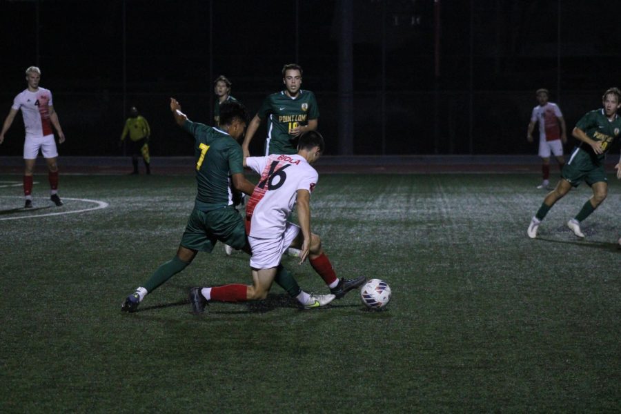Senior midfielder Travis Coombs dribbles away from the Point Loma defender. 