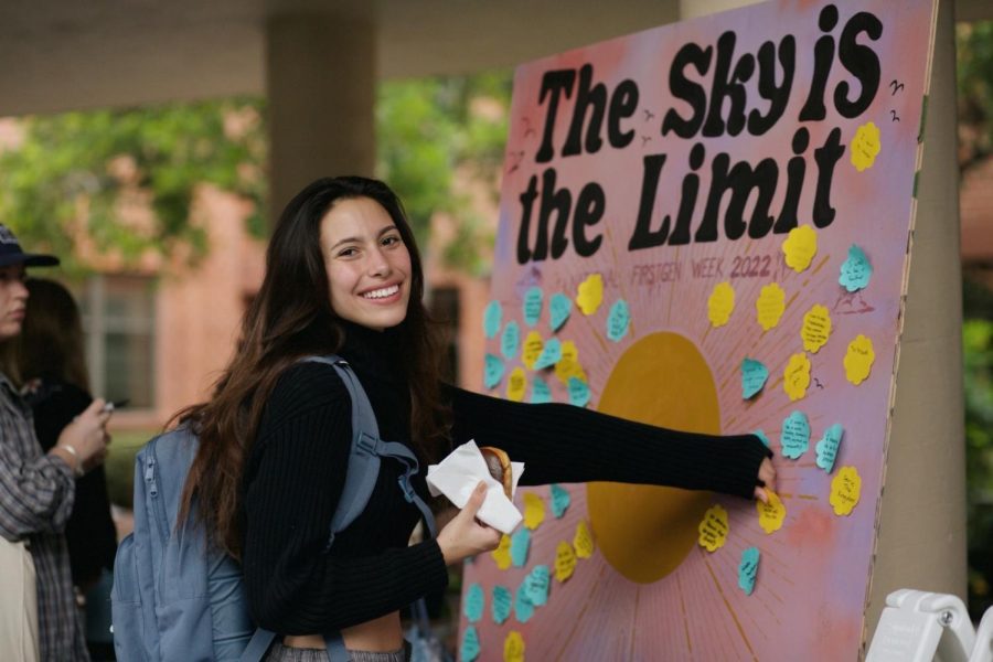 Cinema and media arts major Katherine Padilla puts a sticky note on a wooden board display. 