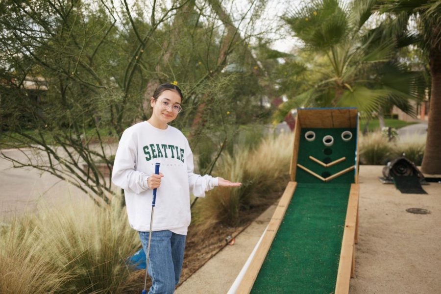 Art major Izah DeFigh stands beside one of the many mini-golf games by Bardwell Hall.
