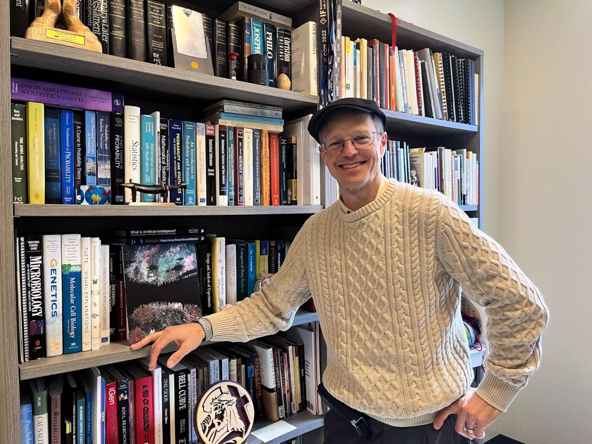 Jason Wilson Professor of Mathematics in front of his collection of books.  