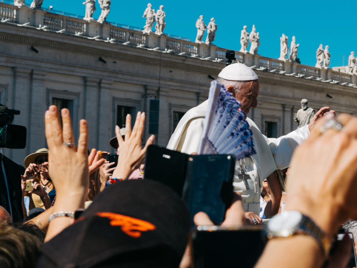 Pope Francis waving his hand to a sea of people